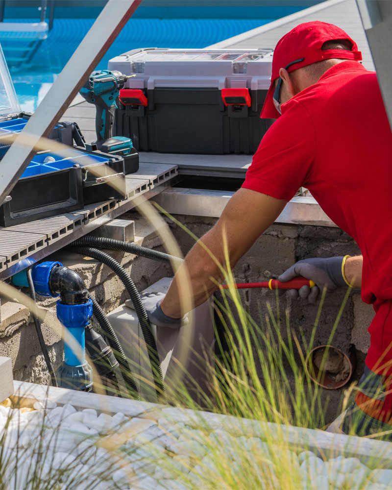 Pool technician diagnosing equipment issues with tools and hoses near a pool, emphasizing professional pool diagnostics and troubleshooting services in Gilbert, AZ.
