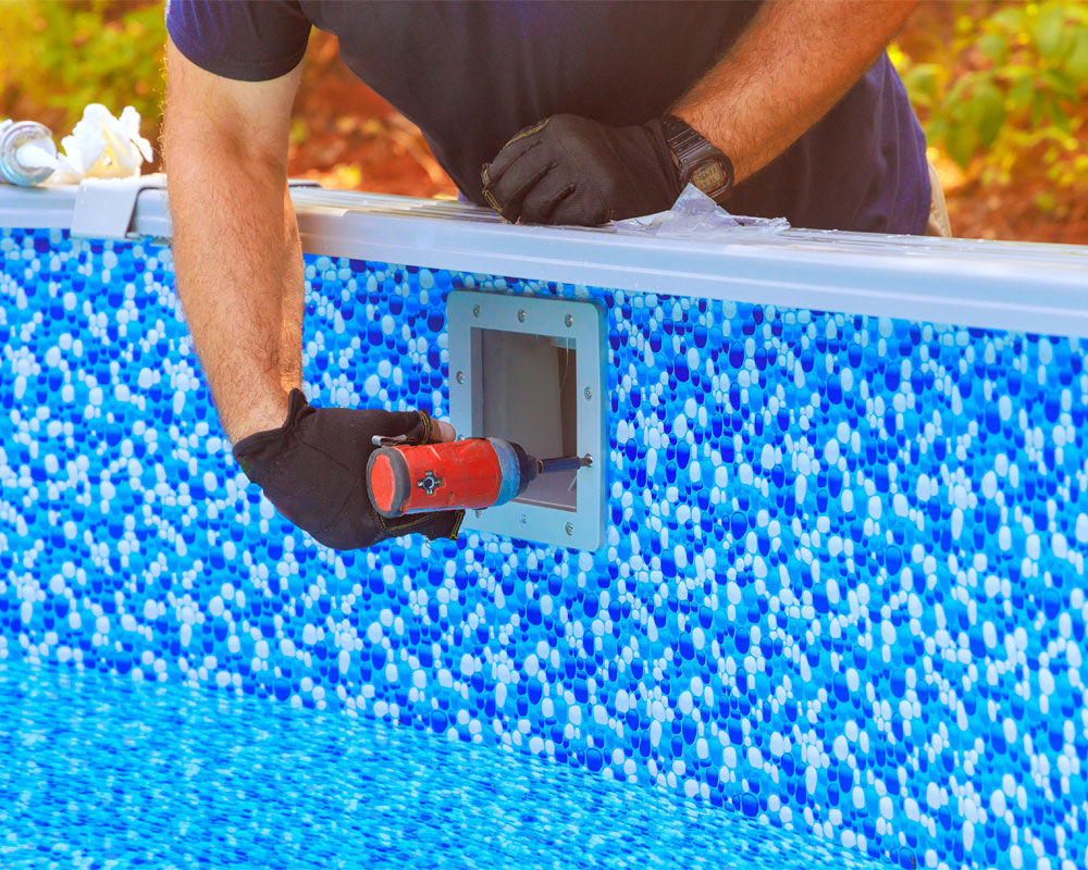 Pool technician performing repair on pool wall with tools, showcasing professional pool maintenance and repair services by Pelican Pools.