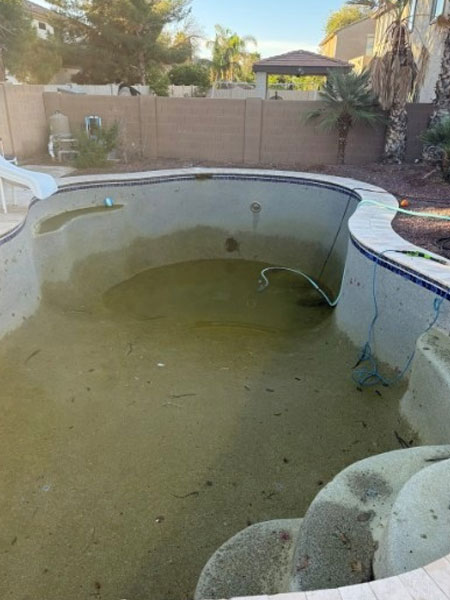 Empty and dirty swimming pool with algae and debris, showcasing the need for remodeling and upgrades to enhance efficiency and aesthetics in Arizona's climate.